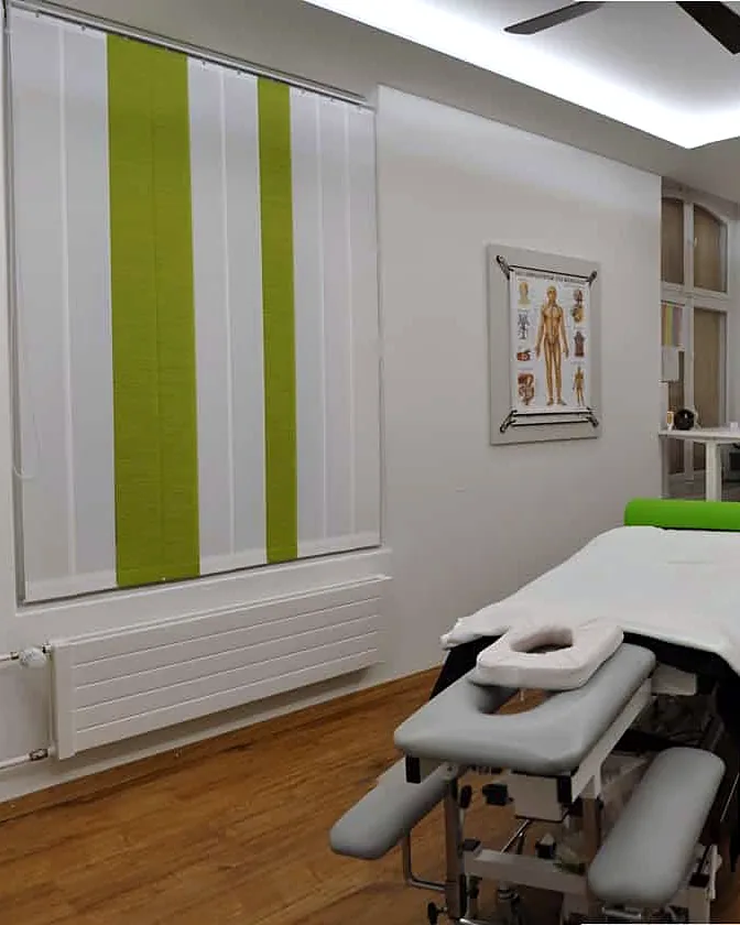 Behandlungsraum mit Massageliege und grün gestreiftem Vorhang